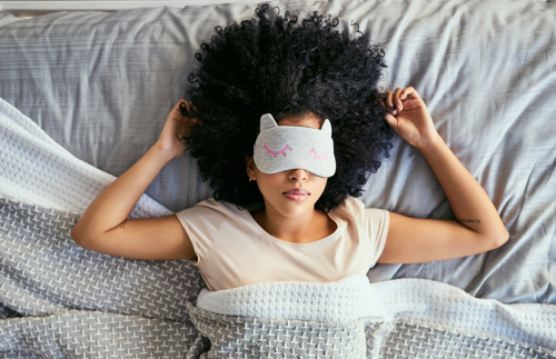 Shot of a young woman sleeping with a mask on in bed